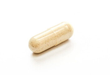 Transparent capsule filled with brown powder. Single pill isolated 