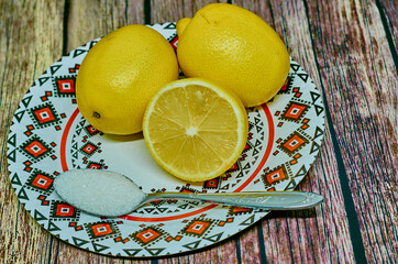 Whole lemons and halves on colored plate on wooden background.