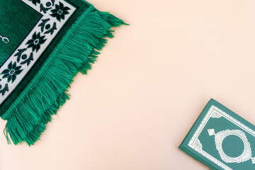 Muslim islamic faith concept Koran book , green rosary, green mat pray . Neutral beige background....