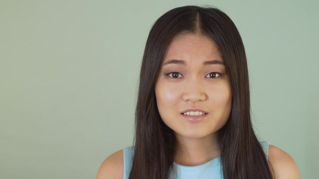 close-up portrait. WHAT? shocked surprised girl looking at the camera. video blue isolated background. 4K