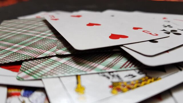 Playing cards drops on a black table, close up, side view.