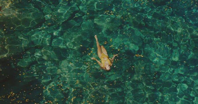 Beautiful young woman relaxing, floating in the ocean, spa wellness lifestyle