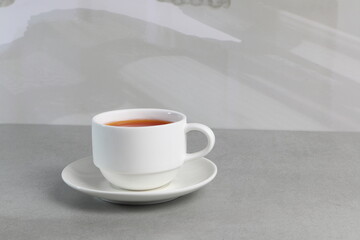 a white cup of coffee on the grey table in the morning