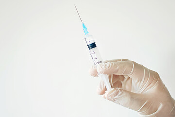 The doctor's hand in a medical glove holds a syringe. Vaccination. Prevention and treatment of diseases. Coronavirus. High quality photo. Epidemic. Space for text