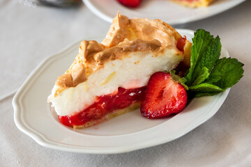 Slice of delicious strawberry tart with meringue on wooden background. Summer food