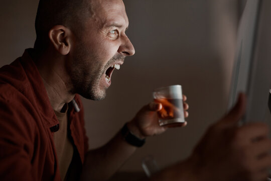 Matue man sitting in front of computer monitor and shouting he drinking alcohol and he has a problem with work