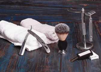 Different safety razors, blade, brush and balsam on a wooden background