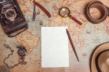 A magnifying glass, an old camera, an ink pen, a belt, a watch, a razor, a hat and paper on a vintage map