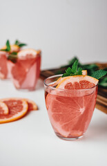 Pink drink, cocktail with grapefruit slice and fresh mint on a white background.