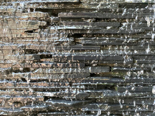Black gray brickblock wall With water flowing like a waterfall, giving a fresh feeling Like nature There is a soft light entering the right hand side. background, wallpaper and backdrop..