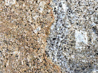 Close-up shot of a large rock with a gray and gold dividing beside the sea that has been eroded by the sea until it is beautiful for artwork or graphic design. wallpaper, background, or backdrop.