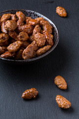 Amêndoas caramelizadas em pote de ceramica sobre pedra de ardósia escura