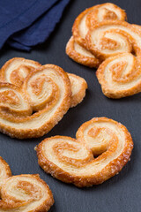 Palmier biscuits dropped on a dark grey stone board and a blue fabric napkin