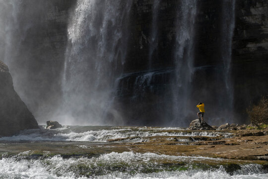 Adventure man looking at Tortum Waterfall in Turkey. Tourist in a yellow jacket relaxing at the Tortum waterfall in Turkey. Landscape view of Tortum Waterfall in Erzurum,Turkey