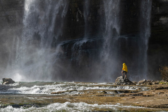 Adventure man looking at Tortum Waterfall in Turkey. Tourist in a yellow jacket relaxing at the Tortum waterfall in Turkey. Landscape view of Tortum Waterfall in Erzurum,Turkey