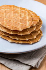 A pile of waffles biscuits on a white plate dish on a wood table