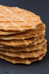 A pile of waffles biscuits on a dark grey stone board