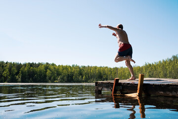 Man jump to lake water having fun during vacation.