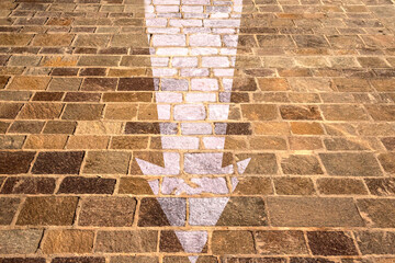 White arrow drawn on the tiles of a pavement