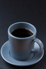 Coffee in a grey cup on a dark grey stone