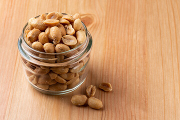 Peanuts in a small glass on a wooden table with empty side space for copy text