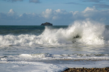 Fototapeta premium Ocean waves crash against rocks on the Cornish coast, England on a sunny February day.
