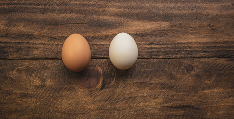 two chicken eggs of different colors on wooden background