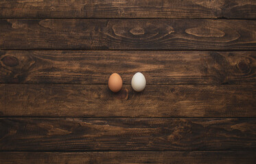 two chicken eggs of different colors on wooden background