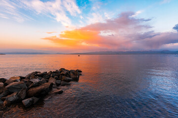 Fototapeta na wymiar Beautiful sunrise on the lake with colorful clouds and stones on the shore. Armenia Sevan lake