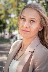Portrait of a successful business woman with blonde long hair. in an expensive suit with a fashionable bag.