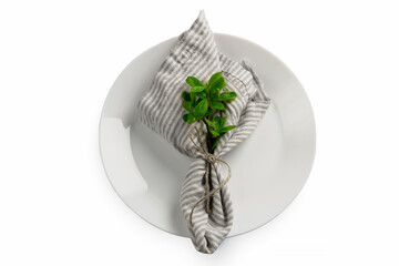One serving napkin with jute rope and ribbon and mint or basil plant laying on clean white table....