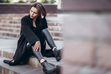 portrait of young woman with short haircut and red lips sitting on the stairs outdoors on the stairs