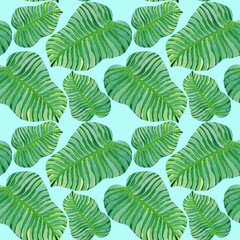 Tropical green leaves seamless pattern on a blue background.