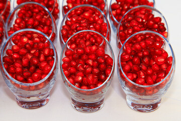 Red pomegranate seeds into glasses on the table