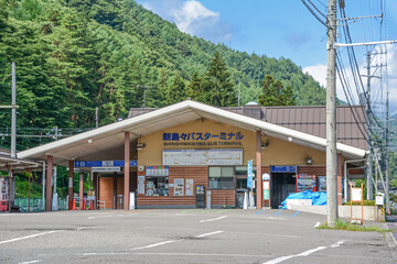 Obraz premium 北アルプス上高地の玄関口、アルピコ交通上高地線、旧松本電気鉄道終点の地上駅、長野県松本市新島々駅の一面二線の島式ホーム、線路、駅名標(隣は渕東)、屋根。さわやか信州号が停車するバスターミナル。The platform of Shinshimashima Station,Matsumoto City,Nagano Pref.