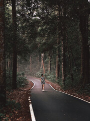 Asian woman walking on the pavement roads that is rainforest in the morning with fresh air.