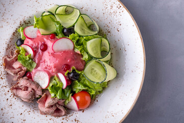Delicious salad with roast beef, vegetables and cranberry sauce on a plate. Top view, text space