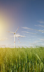 wind mills on a green meadow with blue sky representing sustainable and renewable energy