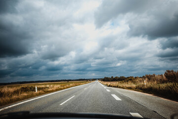 Naklejka premium Blurred asphalt road and dark thunder clouds over it