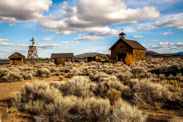 Fototapeta premium Fort Rock, Oregon, a historical school, a windmill and other farm out building located at Fort Rock State Park.