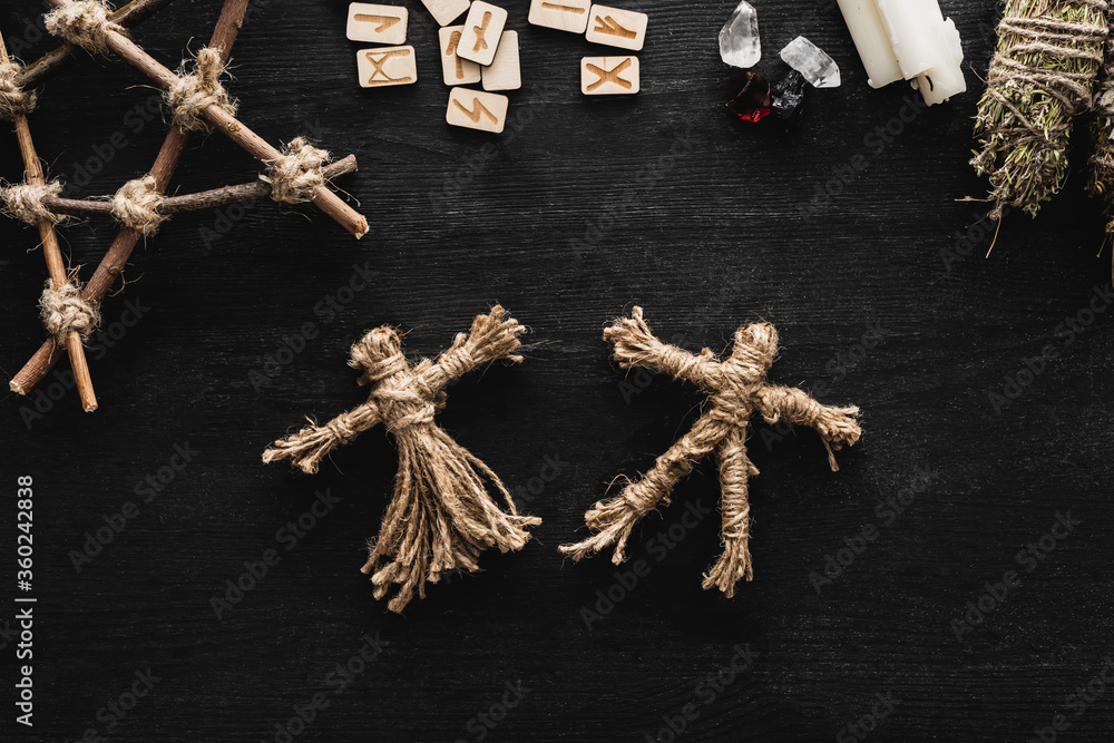 Poster top view of voodoo dolls, scandinavian runes, pentagram, candles and crystals on black