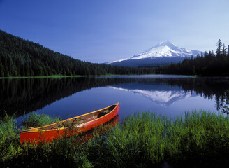 a red canoe on Trillium Lake with snow covered Mt Hood in the background, Oregon Cascade Mountains.
