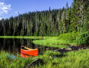 A red canoe on Scott Lake, located in the Cascade Mountains near the summit of the McKenzie Pass,...