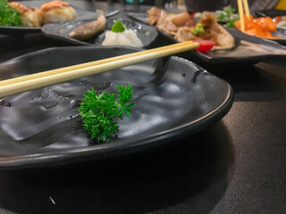 Black plate with chopsticks and green vegetables