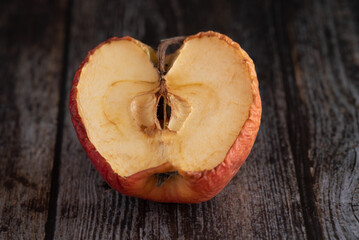 Red wilted rotten half apple details. Close up photo.