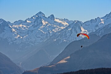 red paraglider with snowy peaks