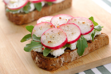 Toasts with ricotta cheese, arugula and radish closeup. Horizonal orientation.