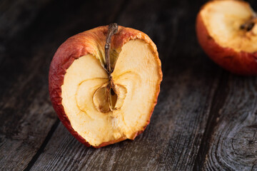 Red wilted rotten half apple details. Close up photo.