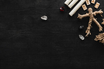 top view of candles near crystals, voodoo doll and runes on black