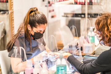Manicure and pedicure salon, coronavirus, covid-19, social distance. The reopening due to the pandemic, security measures. Female worker with mask in nail salon